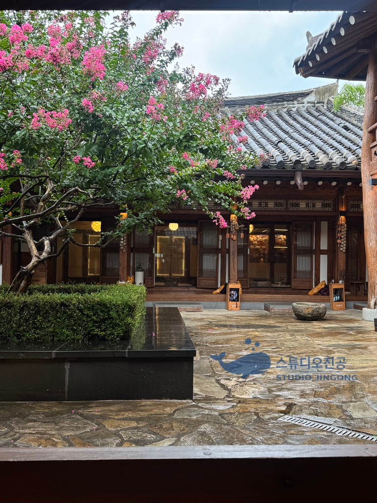Flowers and wet stone paving in the hanok courtyard at Ireuri